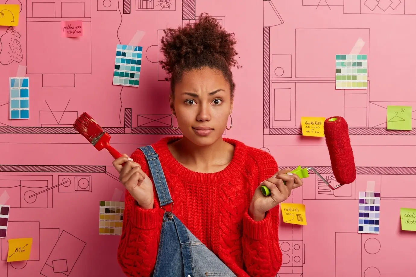 Eine Malerin oder Dekorateurin hält Pinsel und Farbroller, verbessert das Haus, streicht die Wohnung nach dem Umzug, ist mit der Hausrenovierung beschäftigt und posiert vor einer Designskizze. Streichen und Neugestaltung.